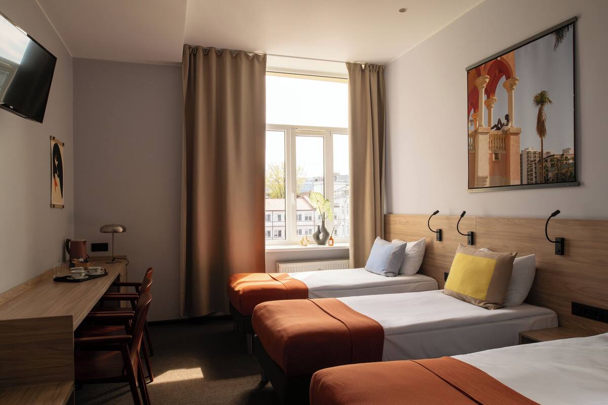Ett hotellrum med två sängar, ett skrivbord och en TV.