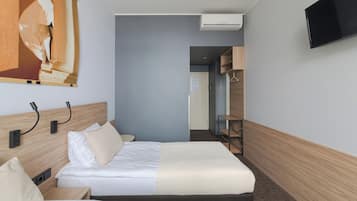 Una habitación de hotel con cama, mesitas de noche, televisión y armario.