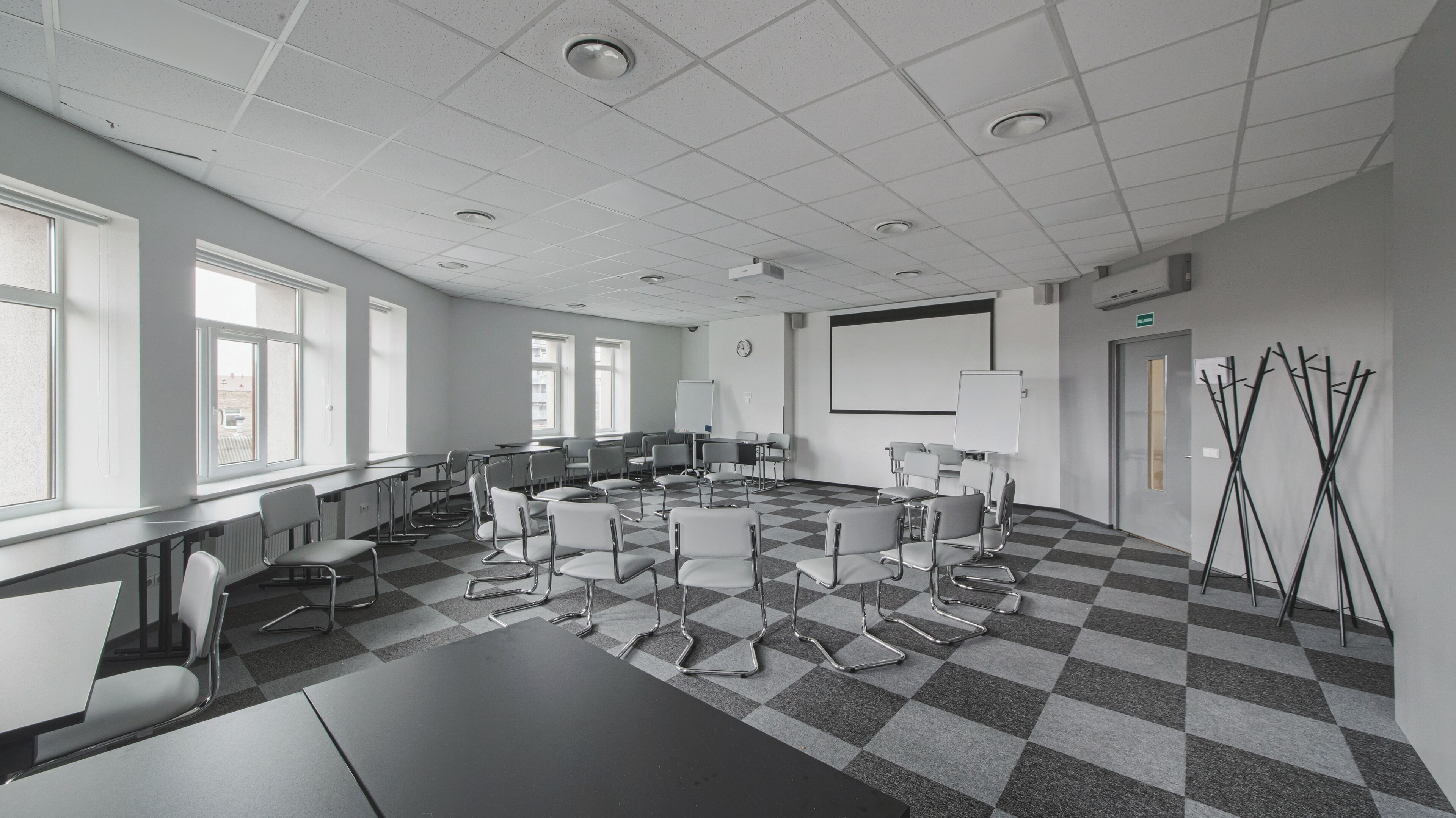 Ett konferensrum med ett rutmönstrat golv, vita väggar och en projektorduk.