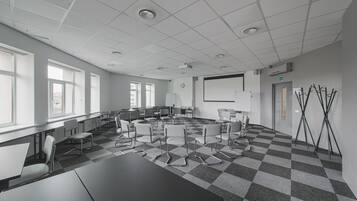 Ett konferensrum med ett rutmönstrat golv, vita väggar och en projektorduk.