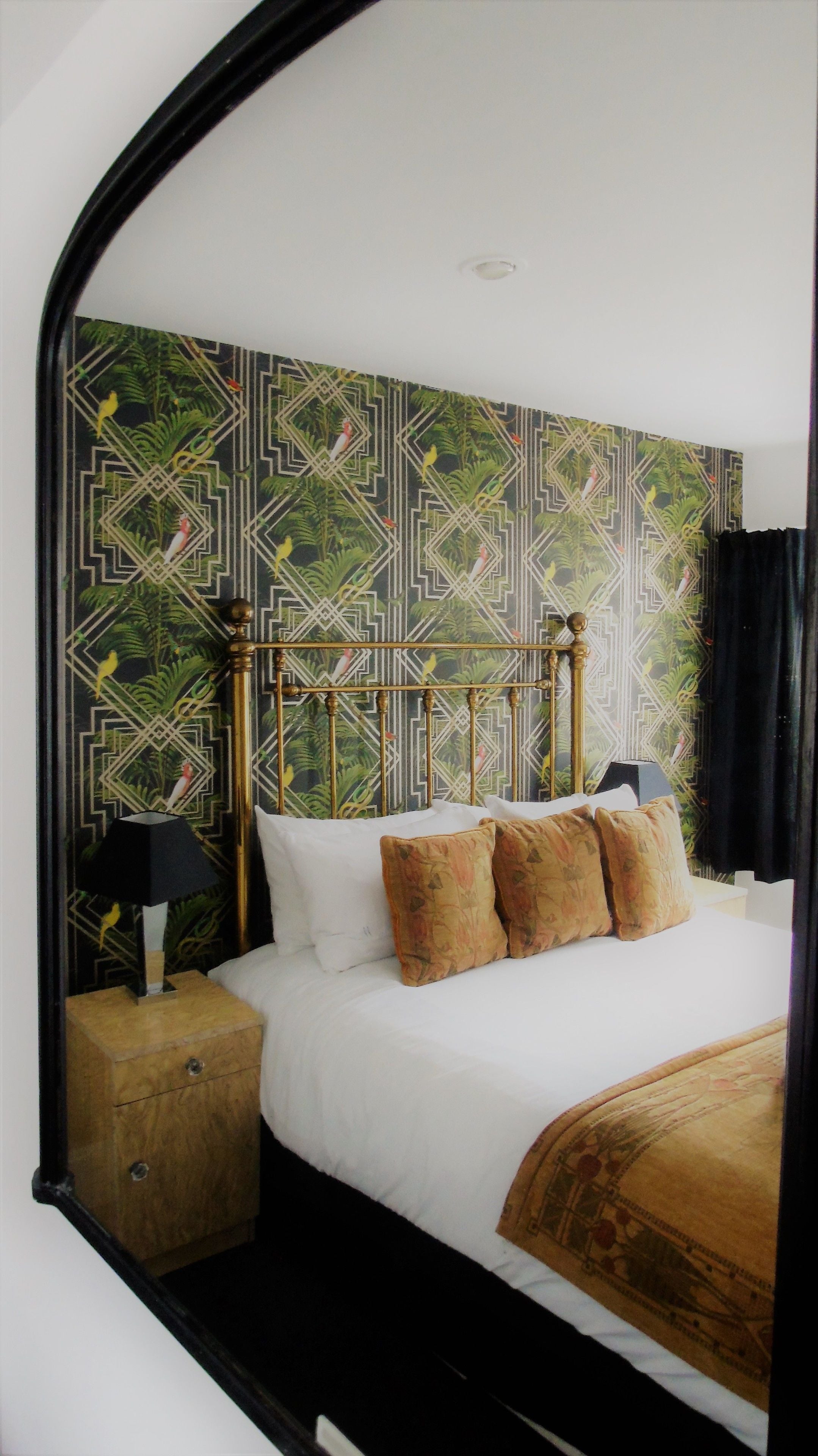 A bedroom with a bed, pillows, a nightstand, and a lamp.