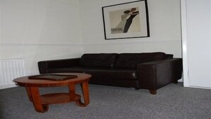 A living room with a dark leather sofa, a wooden coffee table, and a framed abstract painting on the wall. - Paskins Townhouse (Brighton)