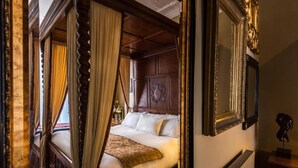 A four-poster bed with a canopy, a wooden headboard, and a nightstand with a lamp. - Paskins Townhouse (Brighton)