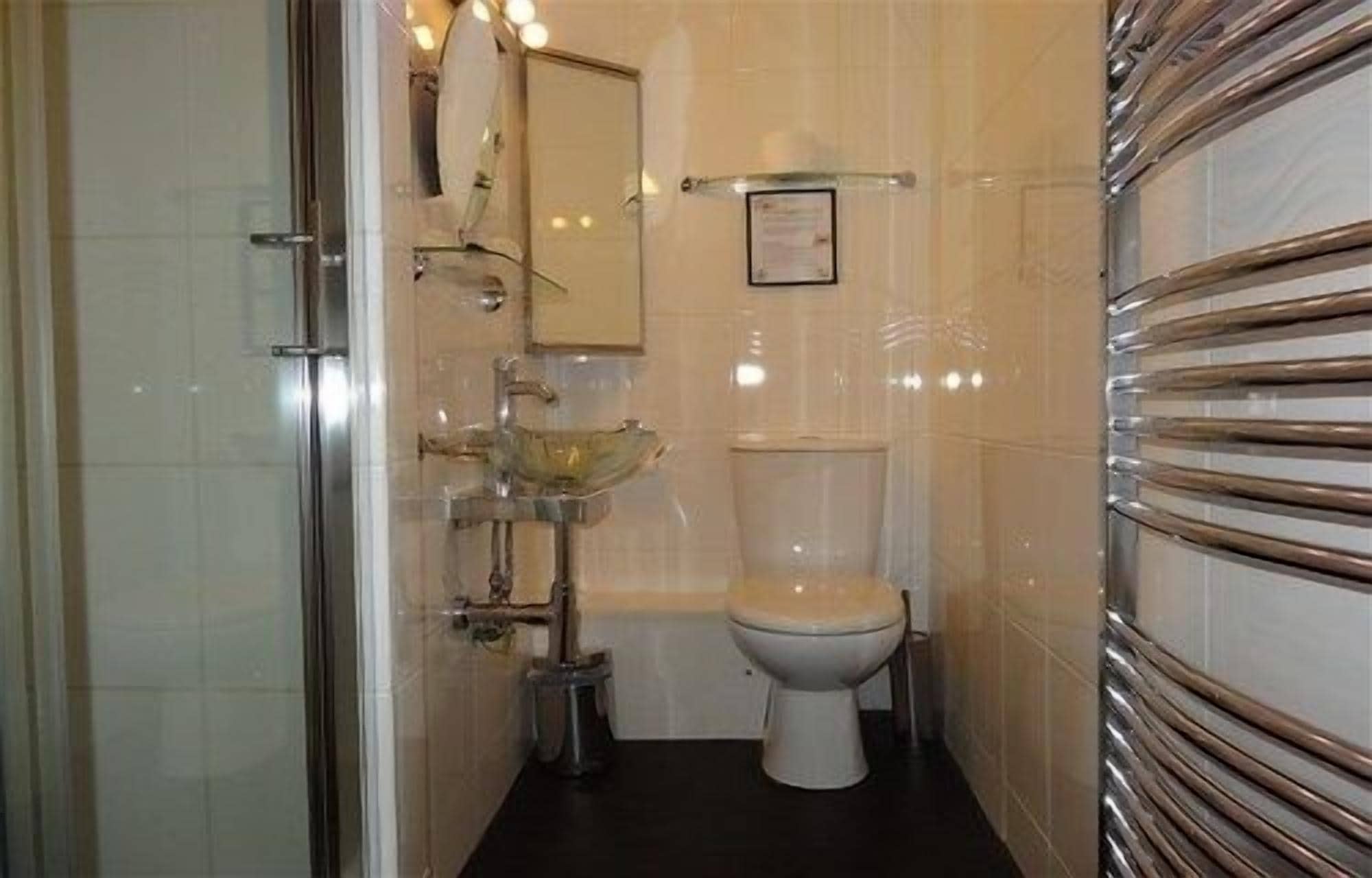 Un baño con ducha de vidrio, inodoro blanco y lavamanos de cristal.