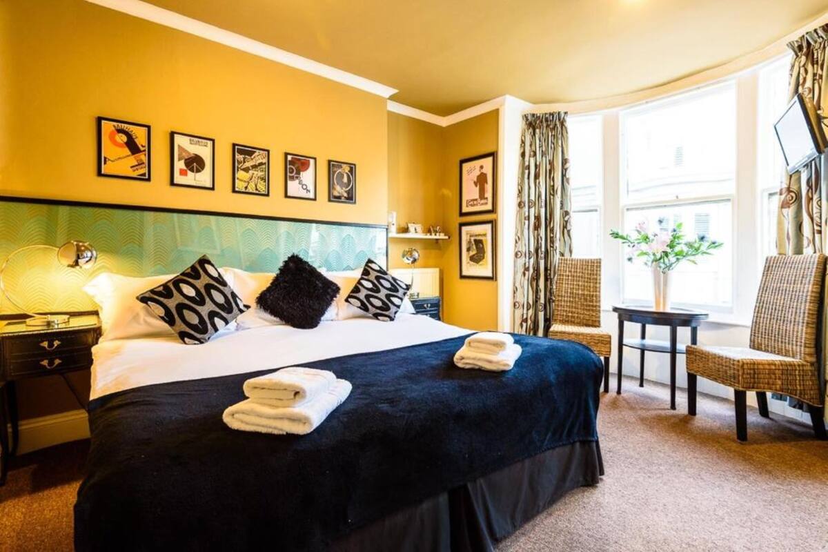 A hotel room with a large bed, a nightstand, a chair, and a small table.