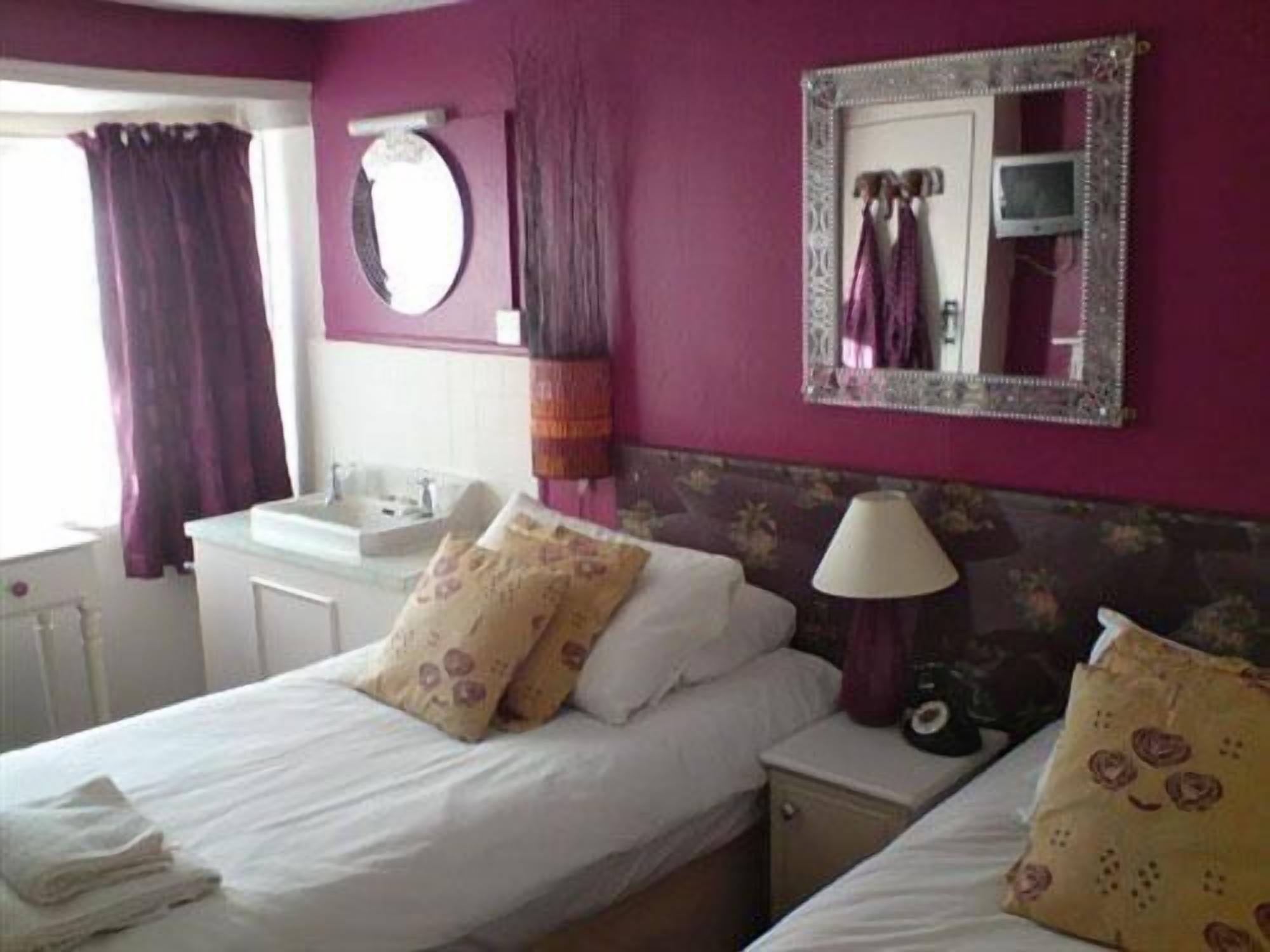 A hotel room with a bed, bedside table, lamp, and a mirror on the wall.