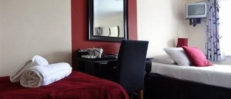 A hotel room with two beds, a desk, a chair, a TV, and a window with curtains.