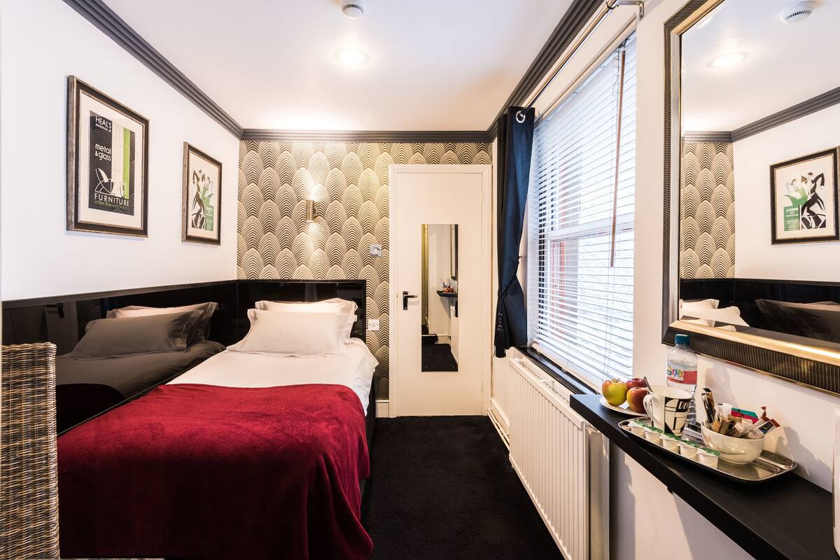 A hotel room with a bed, a dresser, a mirror, and a window with blinds.