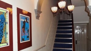 A staircase with blue steps, a chandelier, and two framed posters on the wall. - Paskins Townhouse (Brighton)
