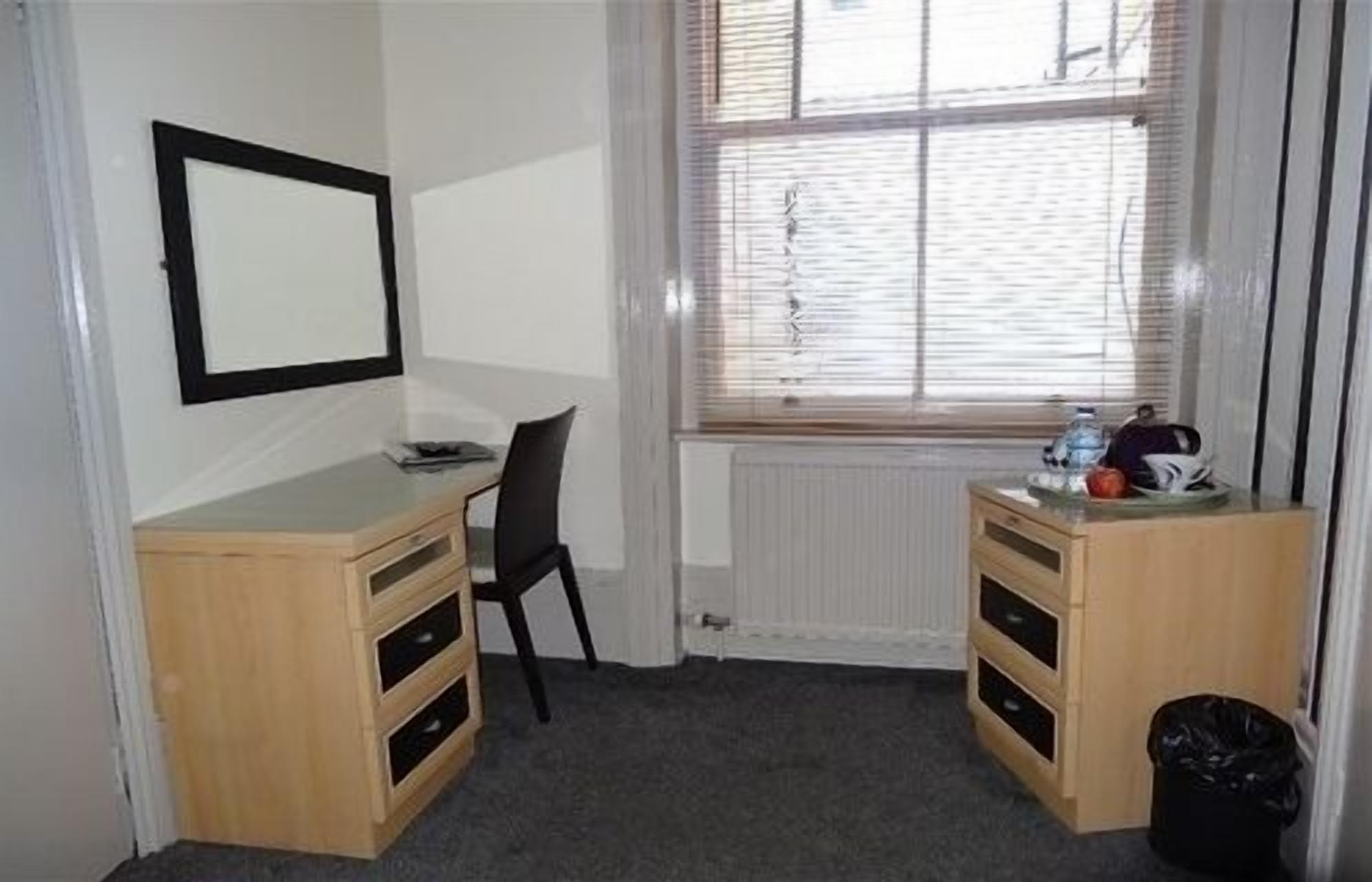 A small, tidy room with a desk, chair, and a radiator.