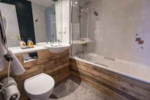 A modern bathroom with a wooden vanity, a white sink, a toilet, and a glass-enclosed shower.