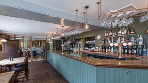 A bar area with wooden furniture, a counter with bottles and glasses, and a stone wall with a 'Lounge' sign. - Duke of Marlborough Hotel (Woodstock)