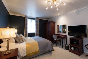 Une chambre d’hôtel équipée d’un lit, d’un bureau, d’une télévision et d’une armoire.