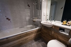 A modern bathroom with a glass-enclosed shower, a wooden vanity, and a large mirror.