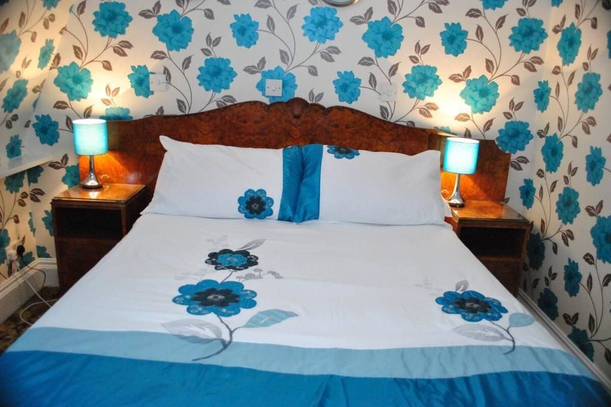 A bed with a floral bedspread, two bedside lamps, and a wooden headboard.