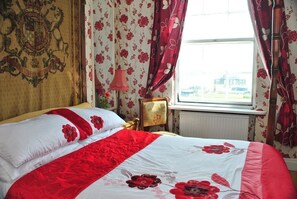 A room with a bed, floral wallpaper, and a window with curtains. - The Prince Regent Hotel (Brighton)