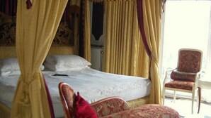A bedroom with a four-poster bed, a chair, and a window with curtains. - The Prince Regent Hotel (Brighton)