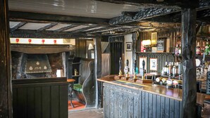 A bar area with wooden beams, a counter with taps, and a sign for coffee and tea. - Queens Head Inn (Penrith)