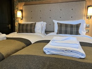 A hotel room with a large bed, two bedside tables, and a headboard with wall-mounted lights.