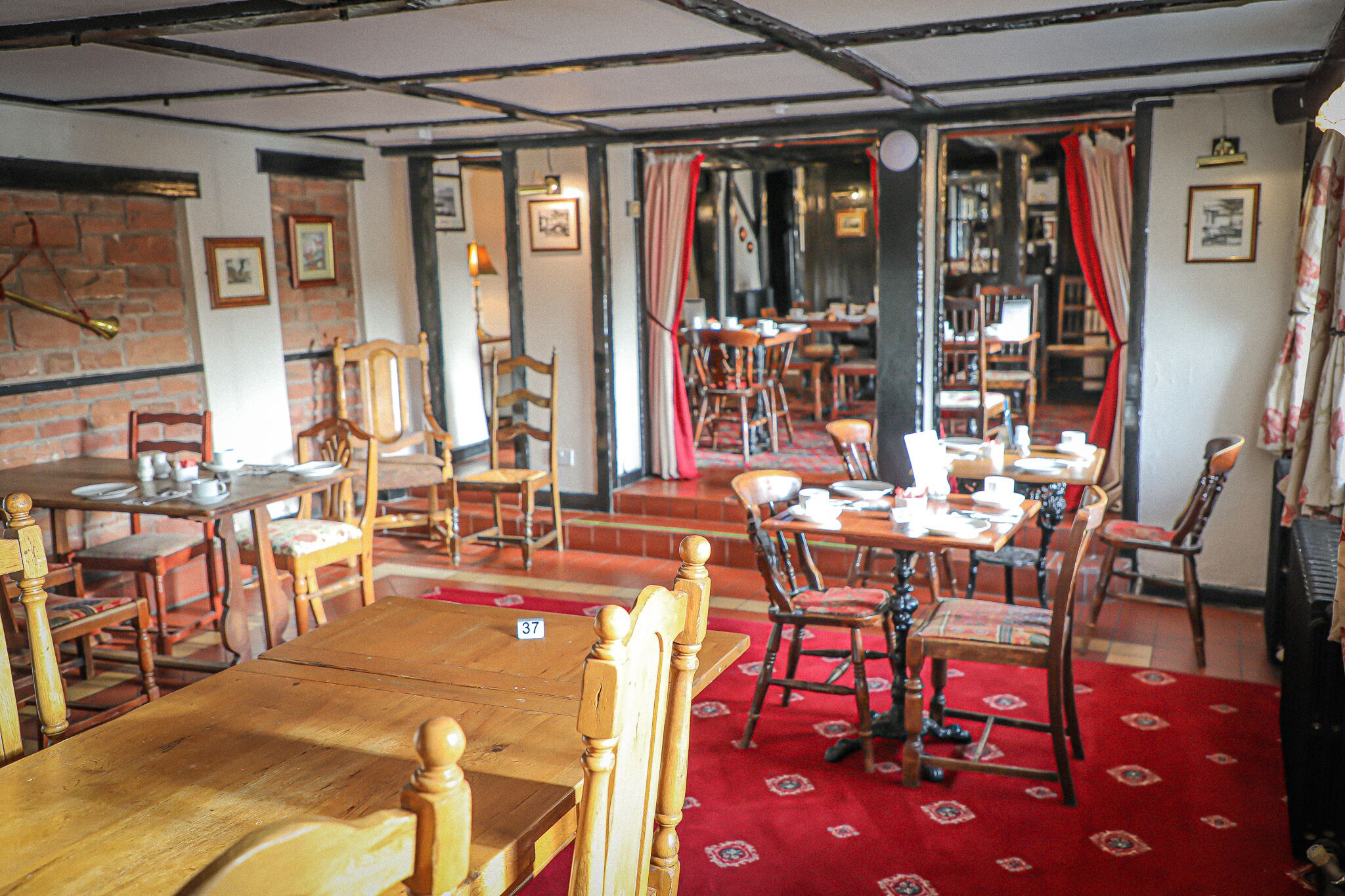 A traditional inn with wooden furniture, red carpets, and brick walls.