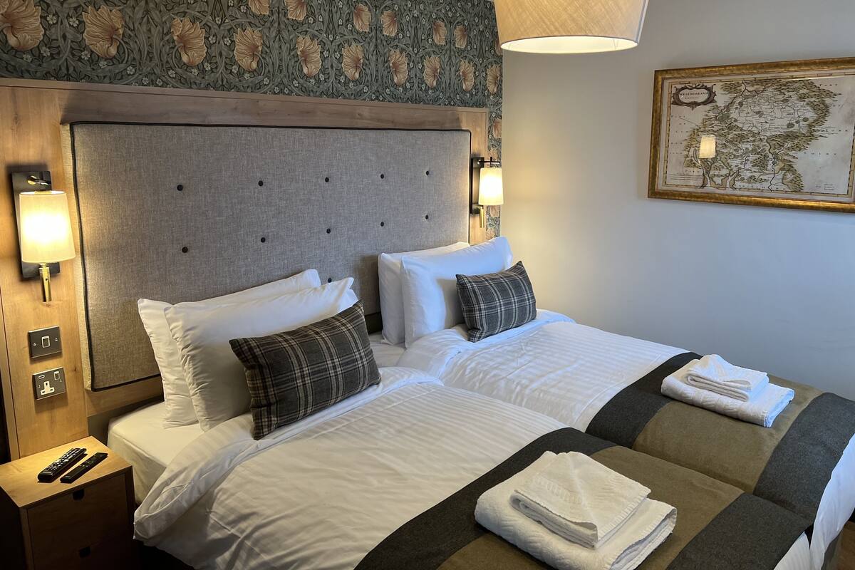 A hotel room with a large bed, two bedside tables, a map on the wall, and a lamp.