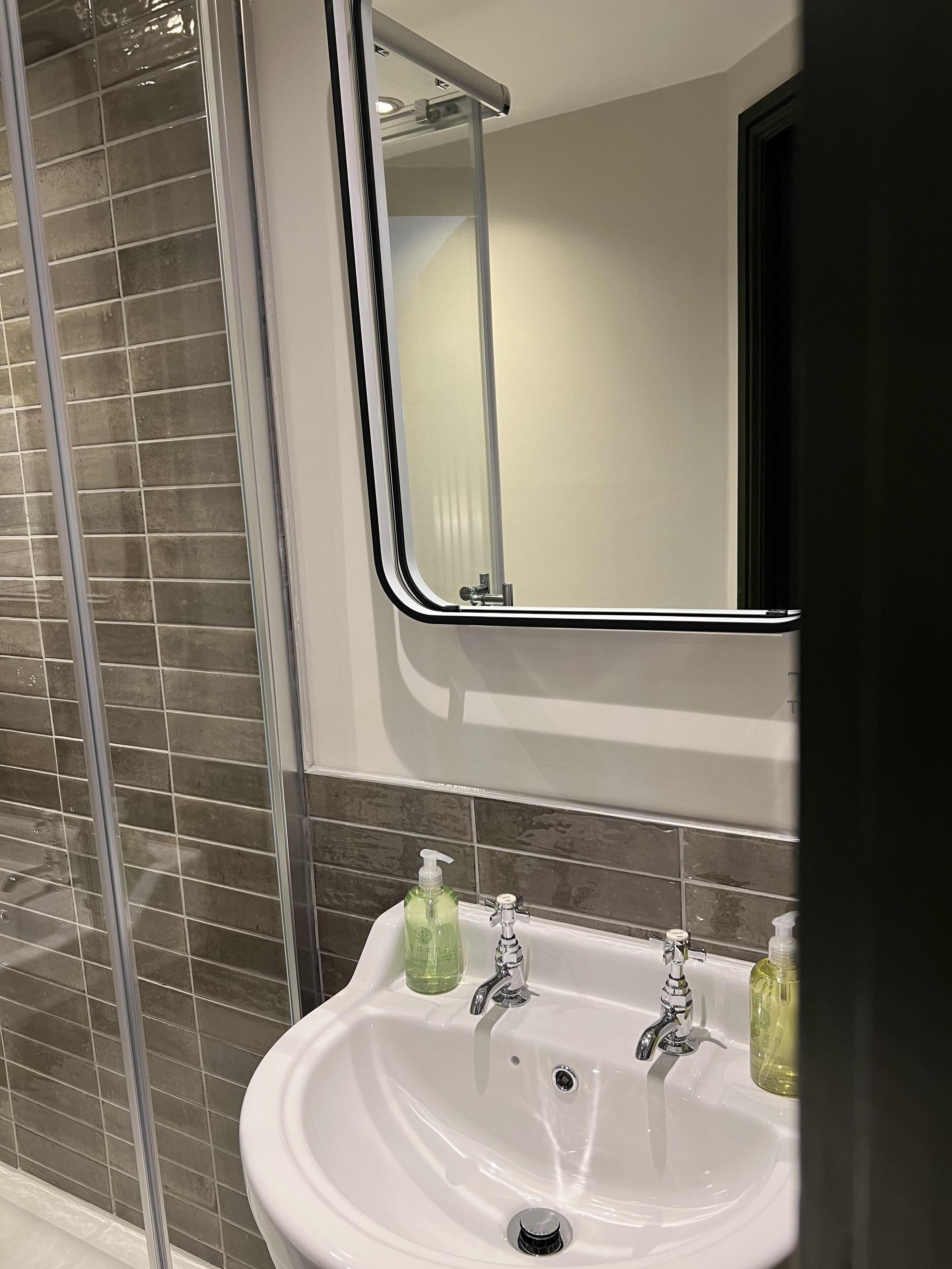 A bathroom with a white sink, two soap dispensers, and a mirror.