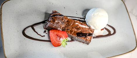 A dessert plate with a piece of chocolate cake, a scoop of ice cream, and a strawberry.