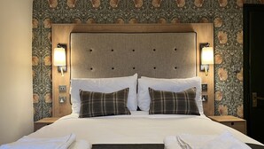 A neatly made bed with two pillows, a headboard with a tufted design, and two bedside lamps. - Queens Head Inn (Penrith)