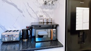 Een moderne keuken met een marmeren achterwand, een zwarte koelkast, een broodrooster, een koffiezetapparaat en een magnetron.