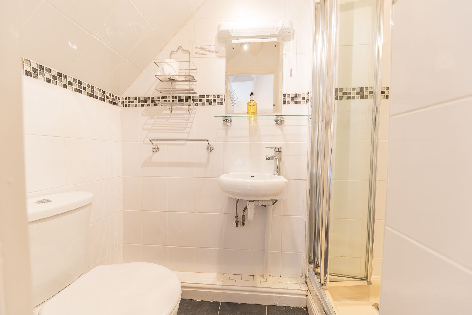Un bagno con un WC, un lavandino, cabina doccia in vetro e porta asciugamani.