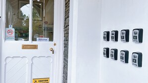 Een witte deur met een rookverbodsgevaarsbord en genummerde keypad panelen op de muur.