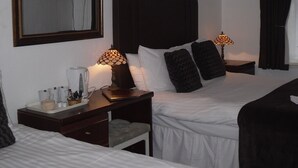 A hotel room with a large bed, bedside tables, a coffee maker, and a TV on the wall.