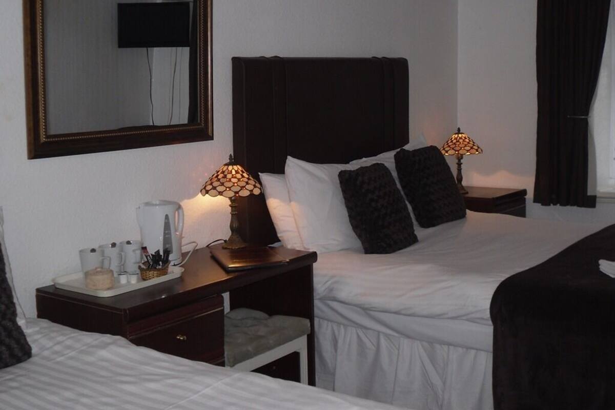 Une chambre d’hôtel avec un grand lit, des tables de chevet, une machine à café et un téléviseur fixé au mur.