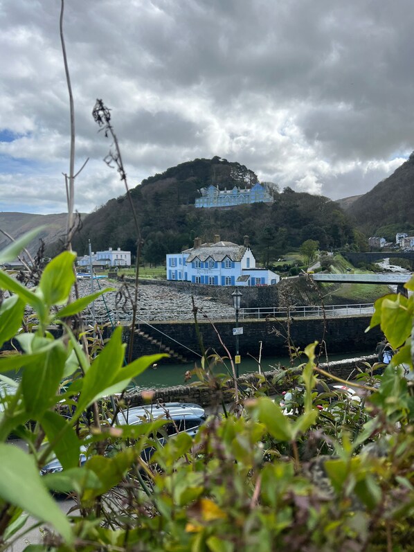 A coastal town with a prominent blue building, a stone bridge, and a hill with a large house. - Rock House Hotel (Lynmouth)