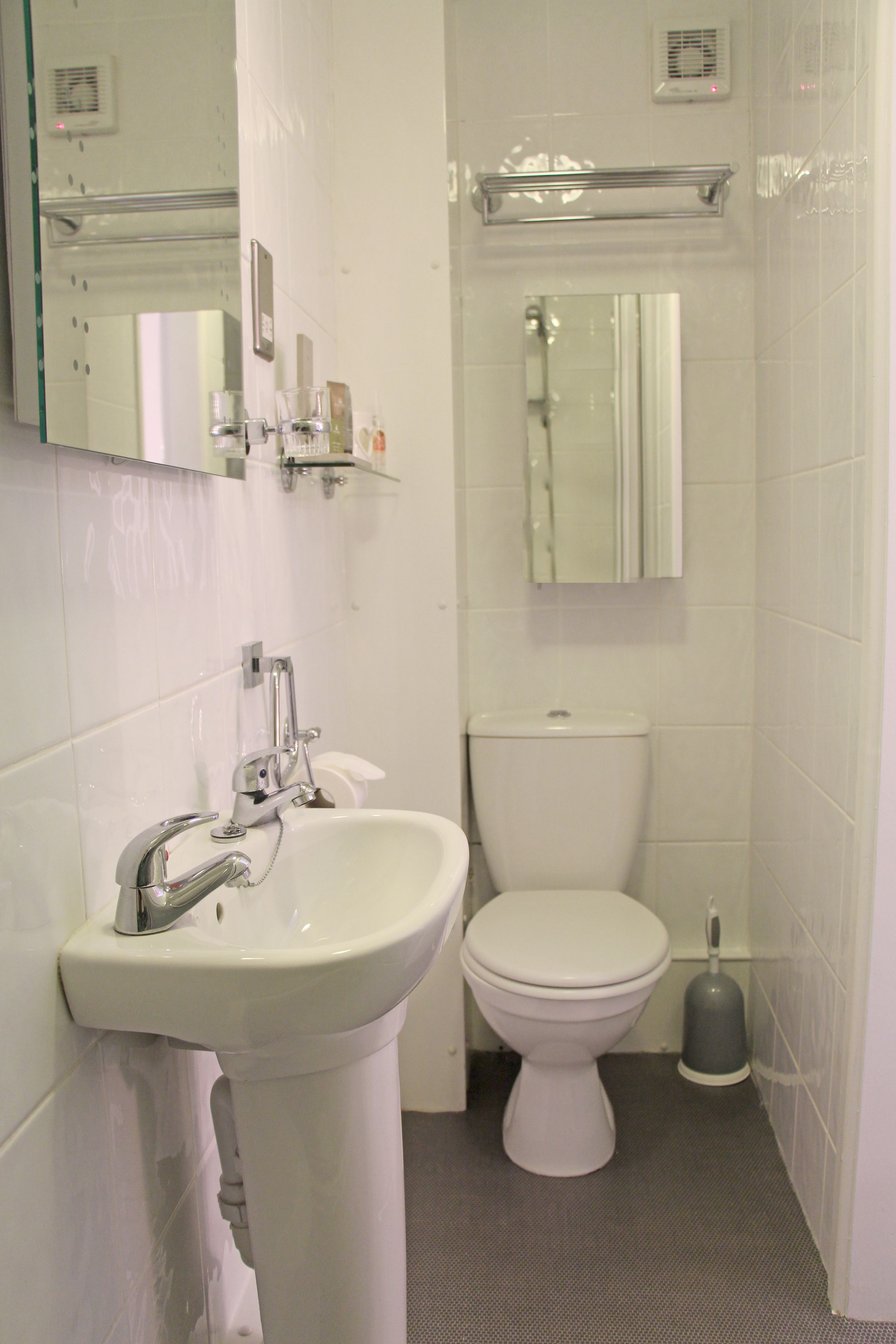 A bathroom with a white sink, toilet, and a mirror above the sink.