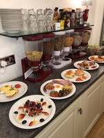 Ein reichhaltiges Frühstücksbuffet mit verschiedenen Speisen, darunter Müsli, Eier und Sandwiches.