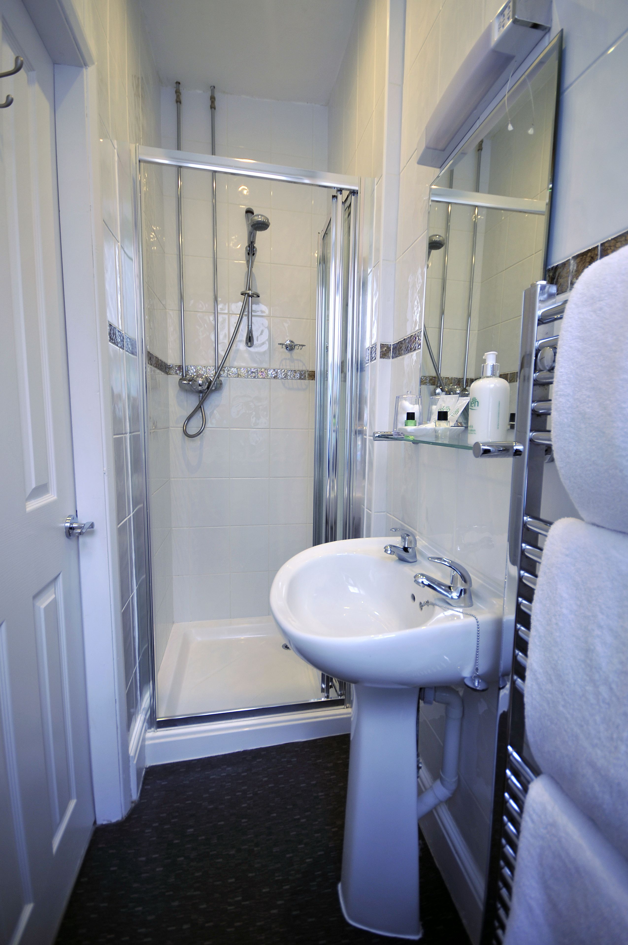 A bathroom with a glass-enclosed shower, a white sink, and a towel rack.