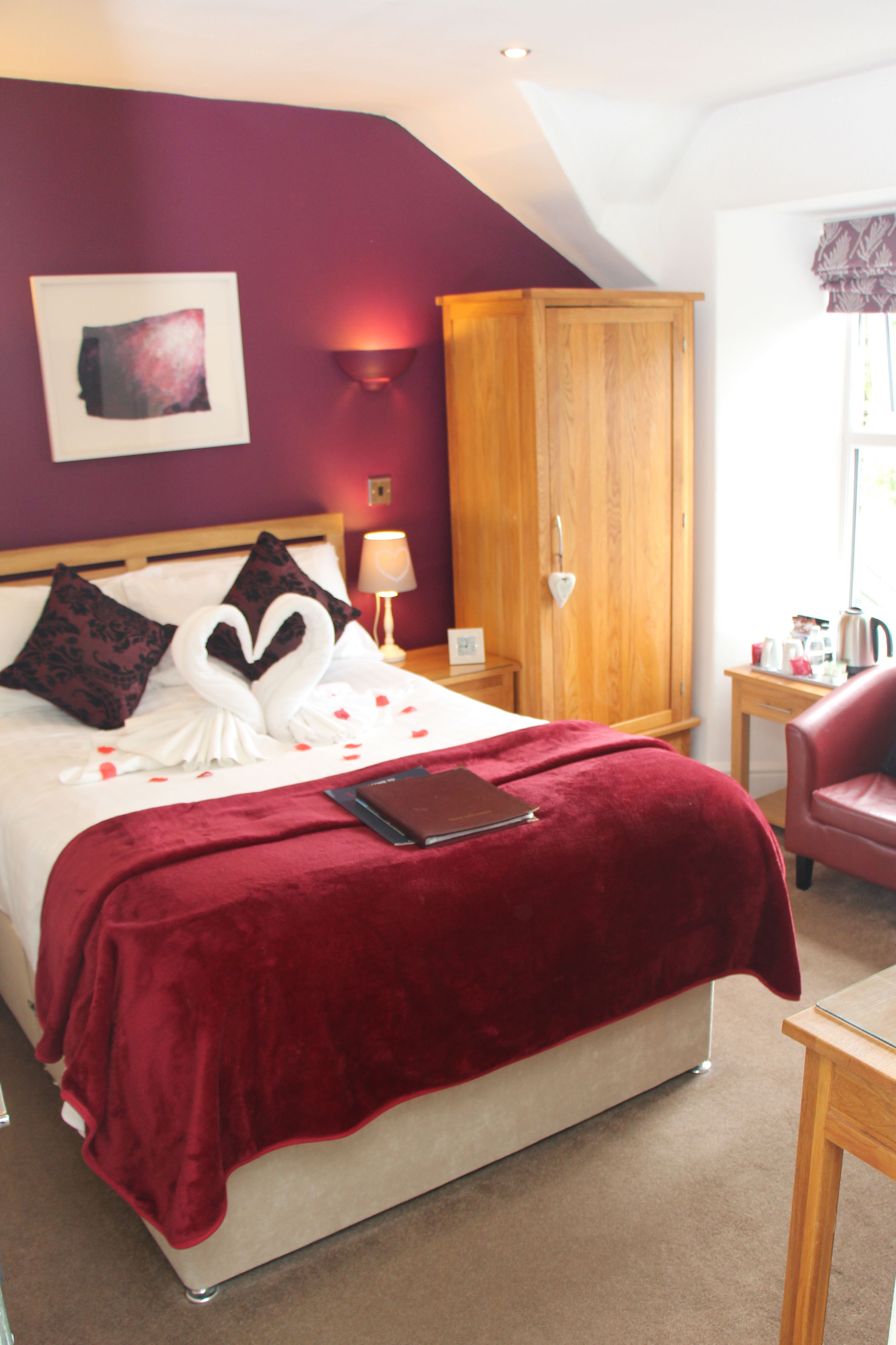 Une chambre à coucher avec un lit, une armoire en bois, une table de chevet avec une lampe et une chaise rouge.