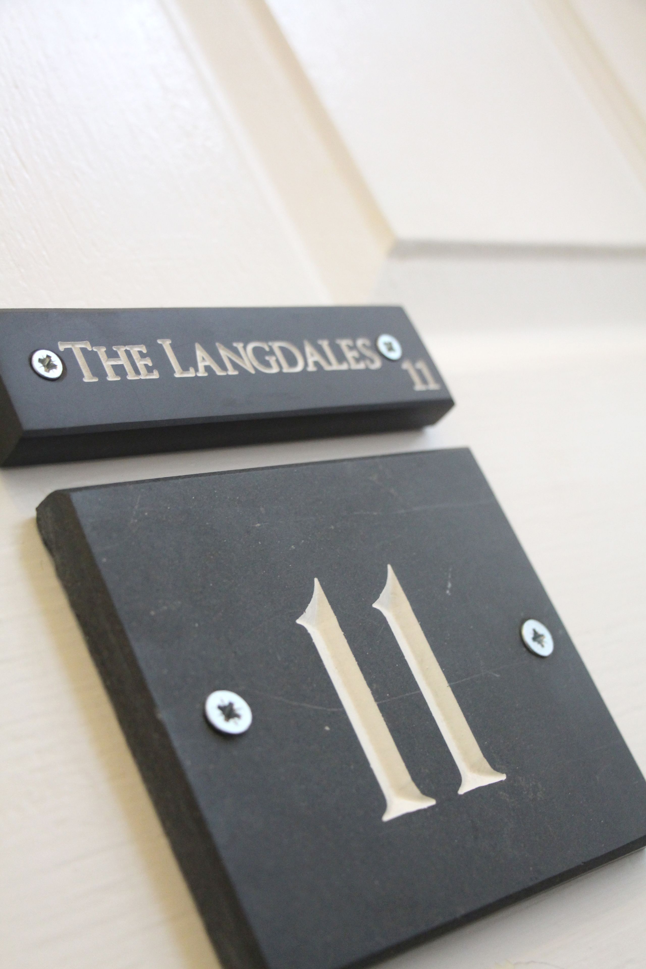 Zwei schwarze Schildchen mit Schrauben, eines beschriftet mit "The Langdales" und das andere mit der Nummer "11".