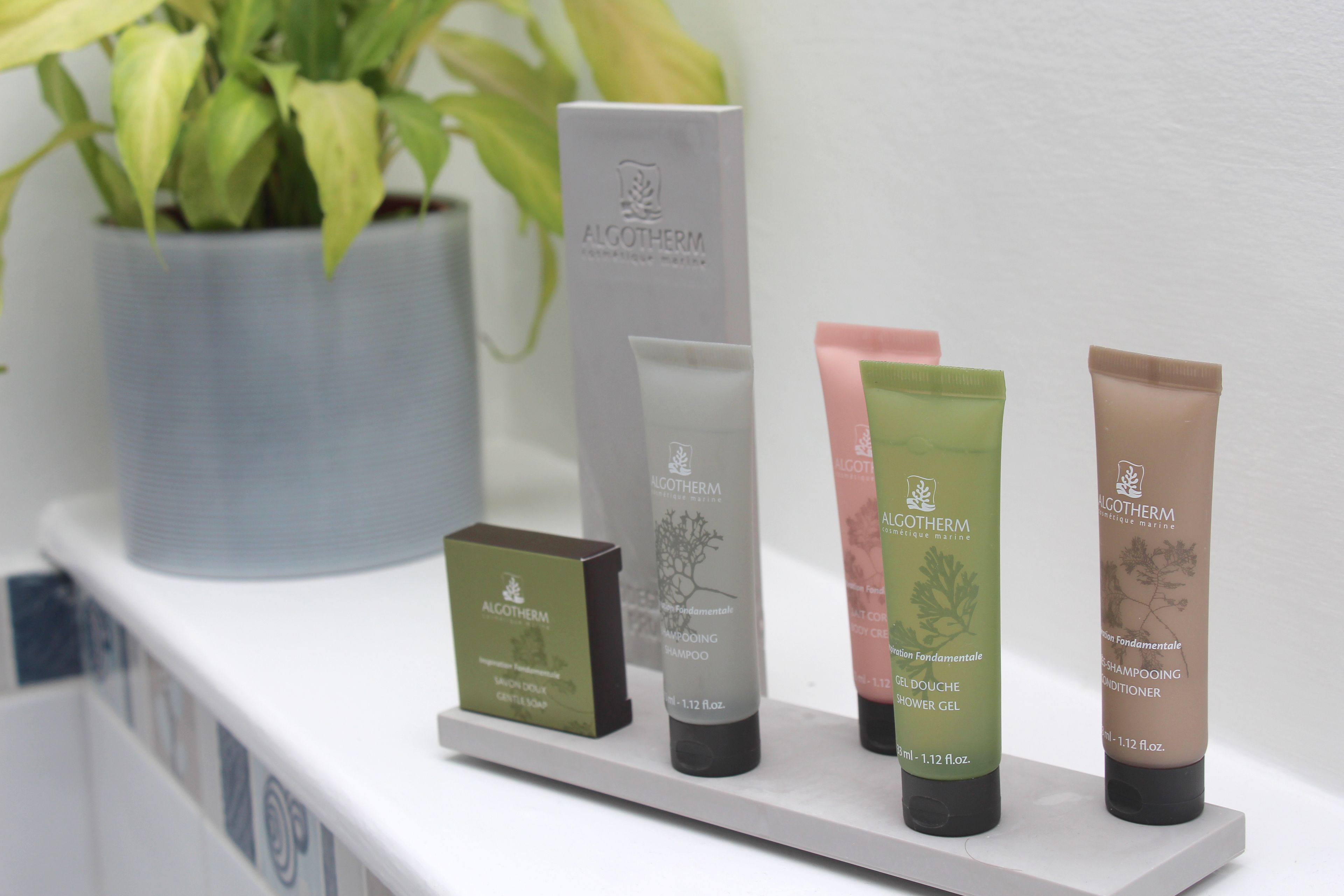 A shelf with various skincare products from ALGOTHERM, including a shampoo, conditioner, and shower gel.