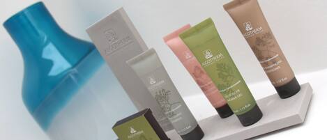 Presentación de productos Alogotherm que incluye un jarrón azul, una caja blanca y cuatro tubos de champú y gel de ducha.