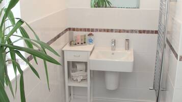 A bathroom with a white sink, a mirror, a towel rack, and a potted plant.
