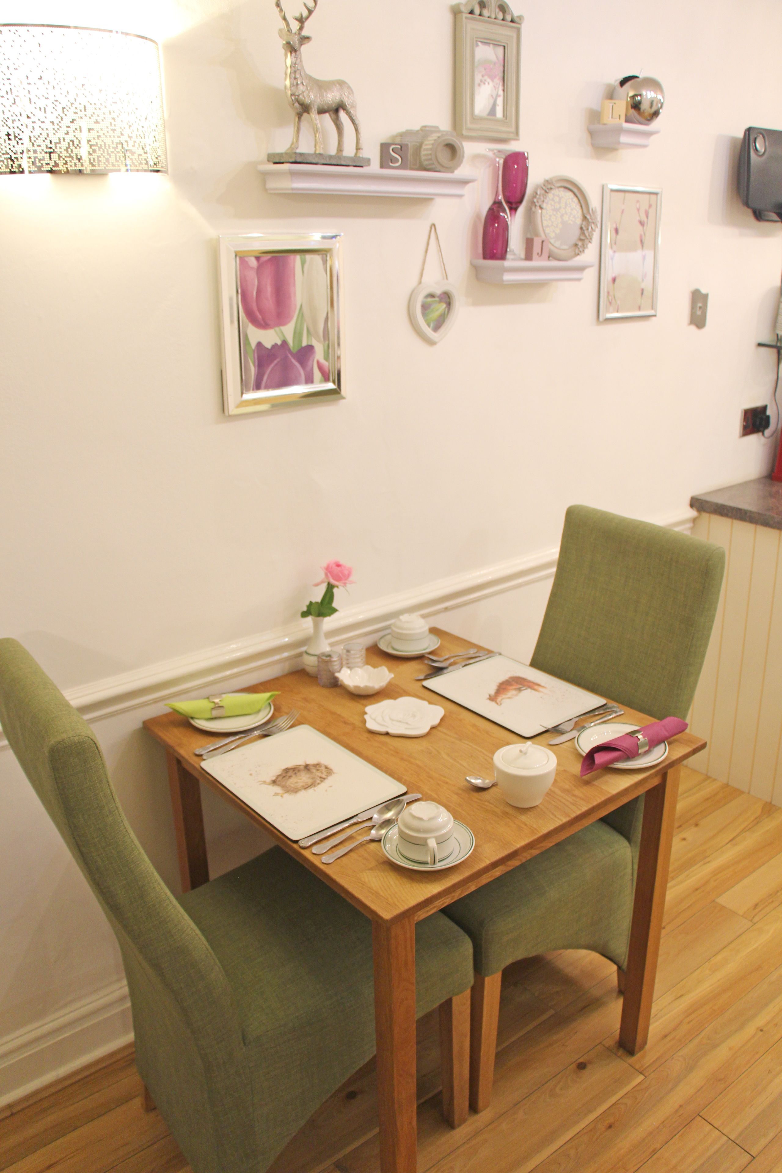 Une table à manger dressée avec des assiettes, des couverts et un vase de fleurs.
