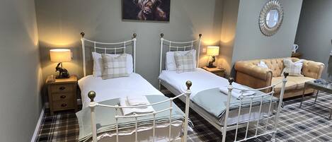 Habitación de hotel con dos camas, un sofá, un espejo y un cuadro en la pared.