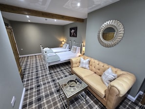 A room with two beds, a sofa, a mirror, and a checkered floor.
