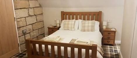 Ein Schlafzimmer mit einem Holzbett, einer Steinwand und einem Holzbalken an der Decke.