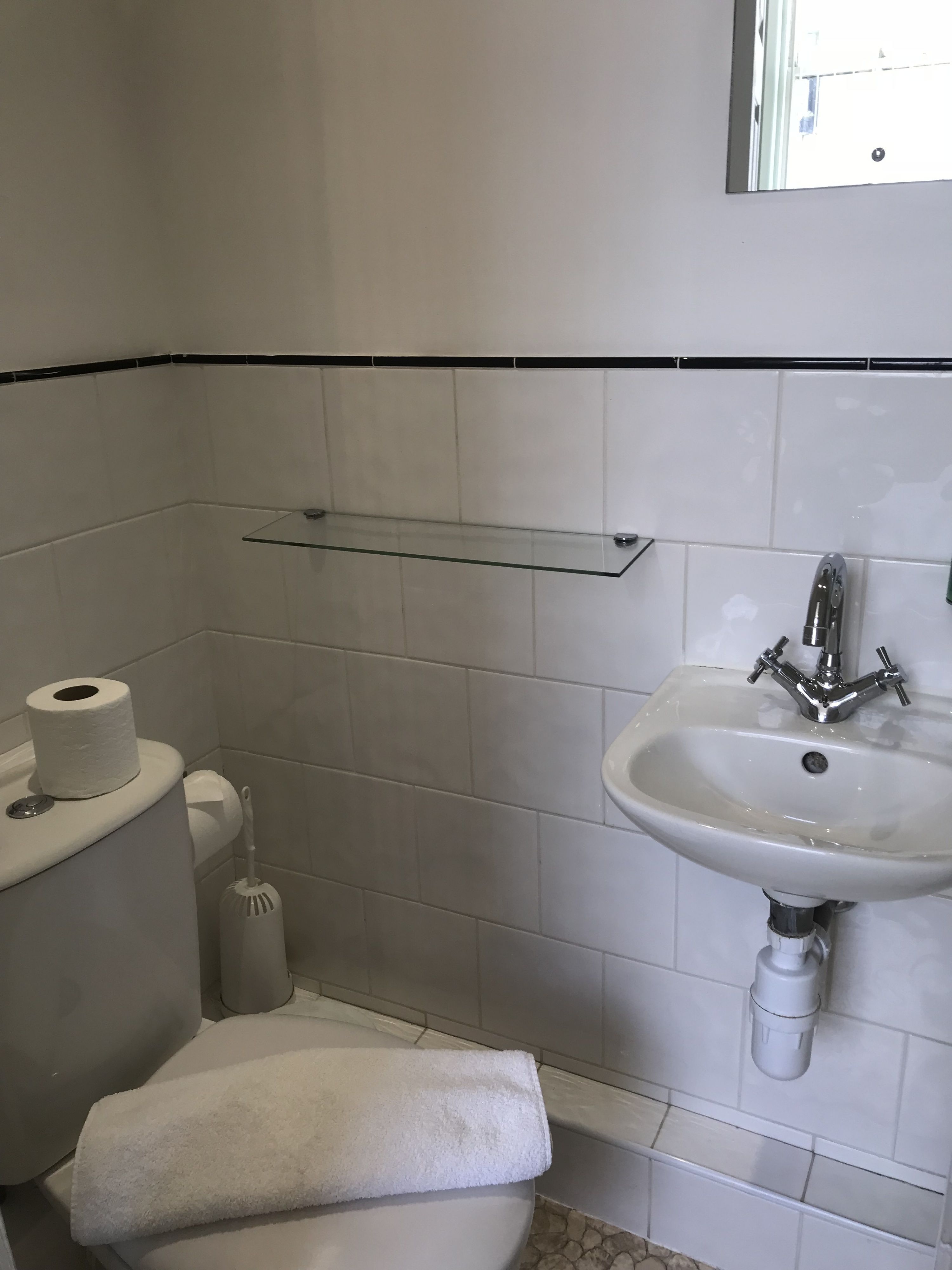 A bathroom with a toilet, a sink, a towel, and a toilet paper holder.