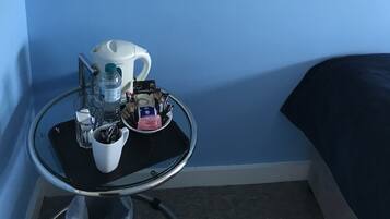 A small room with a blue wall, a round table with a coffee cup, a water bottle, and a mirror.