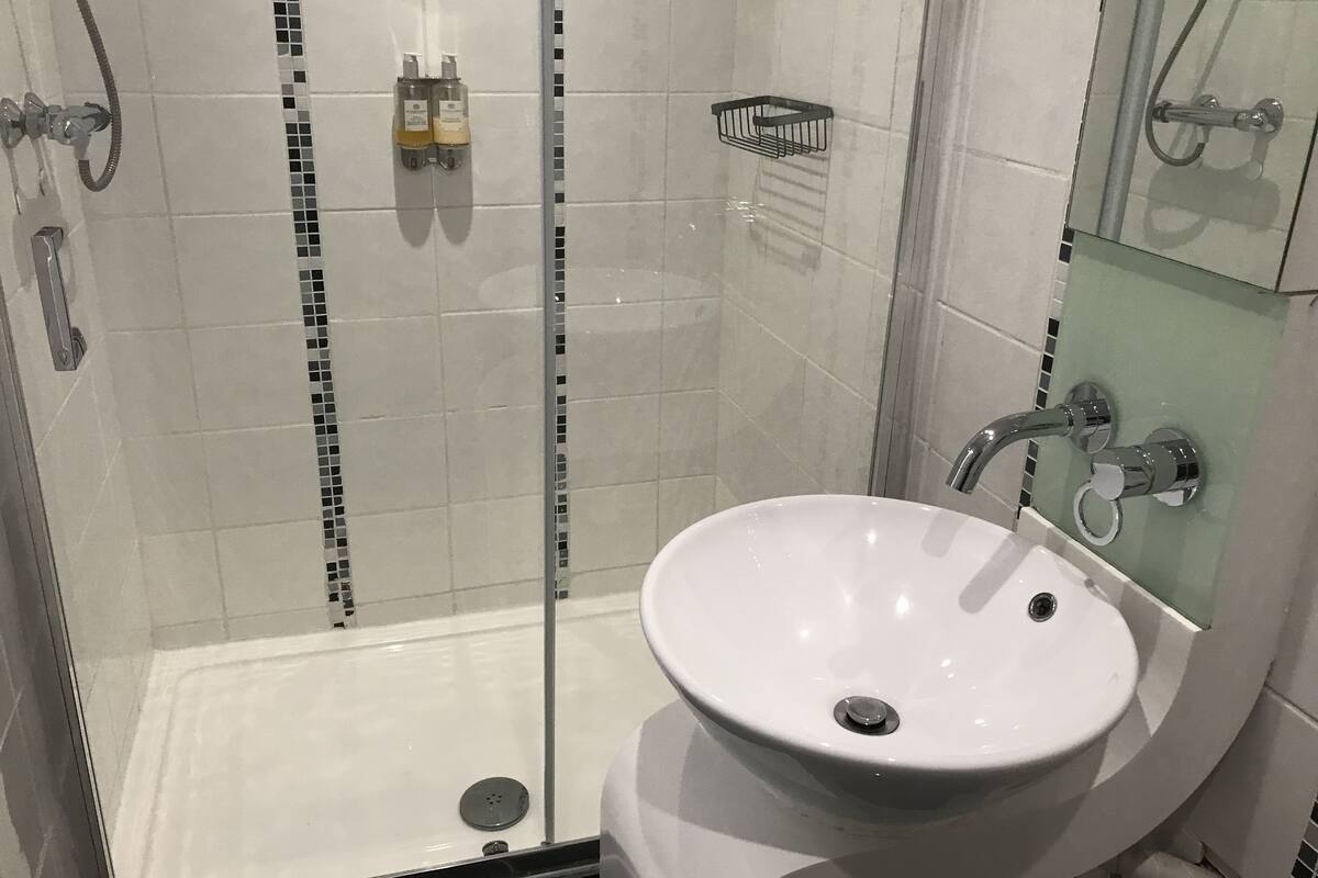 A modern bathroom with a glass-enclosed shower, a white sink, and a mirror above it.