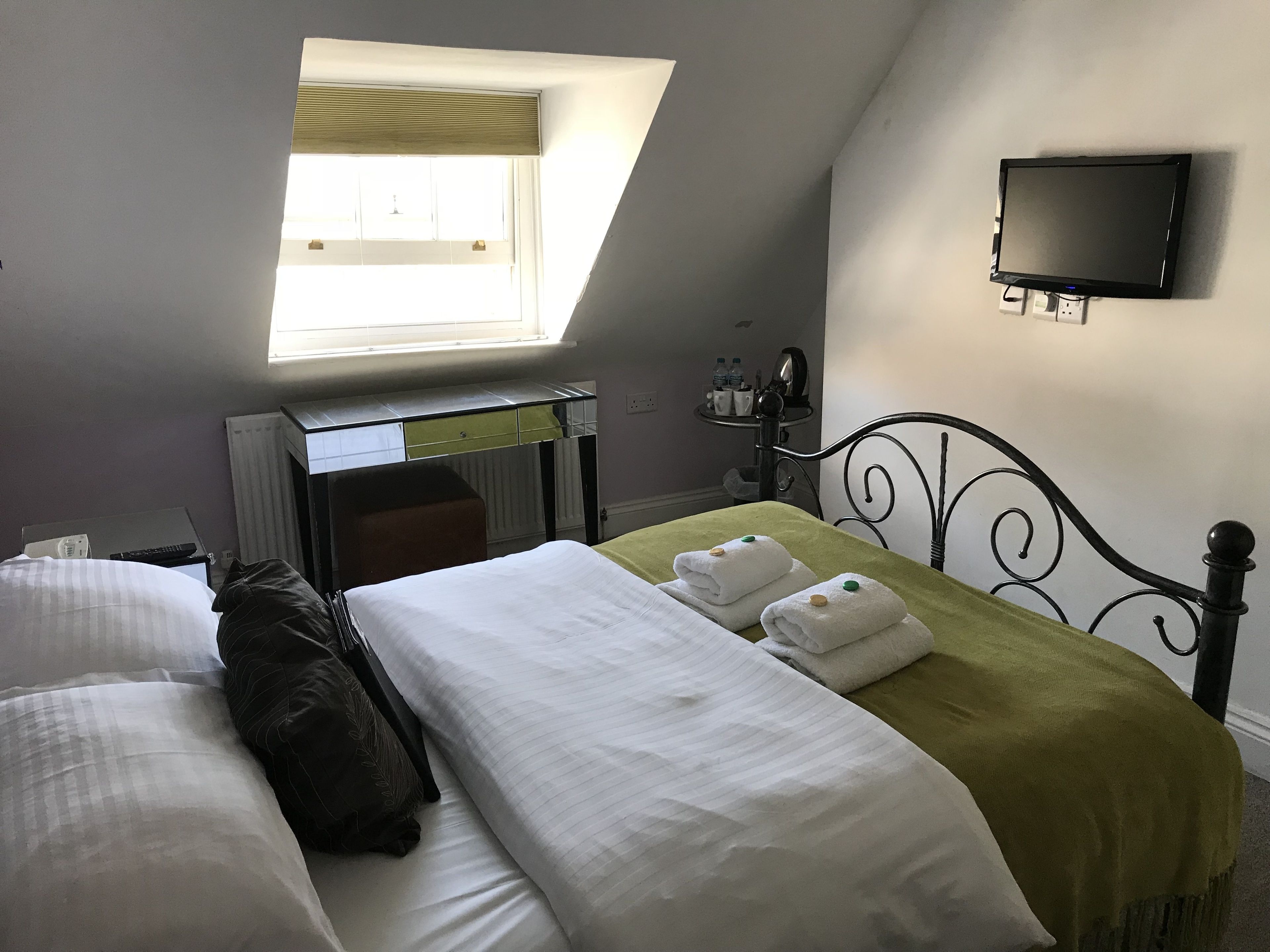 Un dormitorio con cama, escritorio, silla, televisor y ventana.